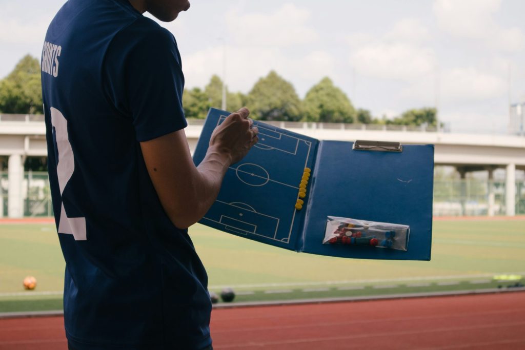 Hombre con camiseta azul de cuello redondo de pie en una pista de atletismo durante el día